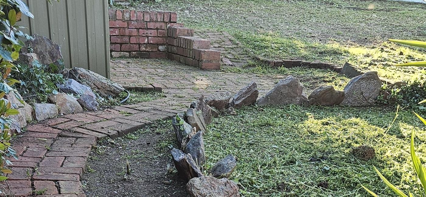 After: side garden cleared with brick path and rock edging uncovered